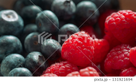 Close-up macro shot of fresh raspberries and blueberries showing natural texture and vibrant colors Close-up macro shot of fresh raspberries and blueberries showing natural texture and vibrant colors 131921694