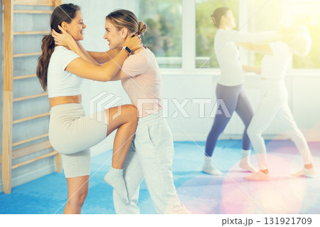 Young woman practicing knee strike to sparring female partner stomach in self-defense training 131921709