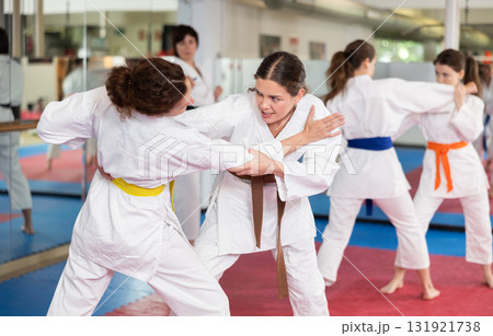 Womens working in pair mastering new karate moves during group class 131921738