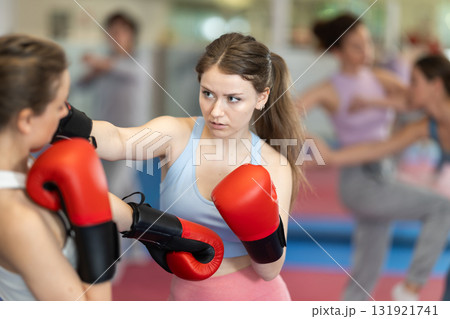 Female co-participant and woman sparring partners during training battle fight using technique of boxing match in sport gym Female co-participant and woman sparring partners during training battle fight using technique of boxing match in sport gym 131921741