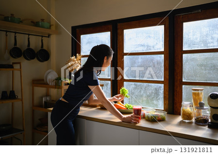 Asian woman standing by the window with fresh ingredients and smoothie Asian woman standing by the window with fresh ingredients and smoothie 131921811