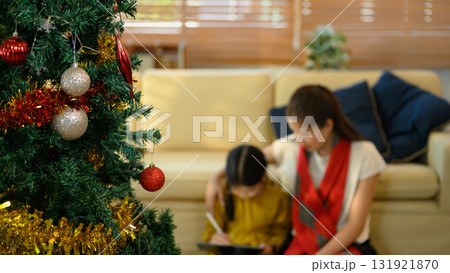Close up of decorated Christmas tree with blurred background of mother and daughter using tablet together 131921870