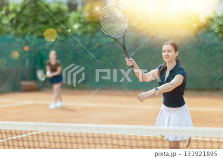 Girl plays tennis on open court with opponent 131921895