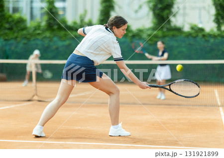 Young woman playing doubles tennis on court Young woman playing doubles tennis on court 131921899