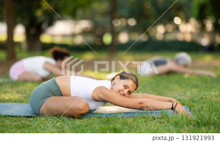 Young female yoga instructor leading outdoor group class Young female yoga instructor leading outdoor group class 131921993