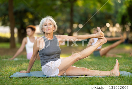 Senior woman performing yoga asanas in summer park Senior woman performing yoga asanas in summer park 131922005
