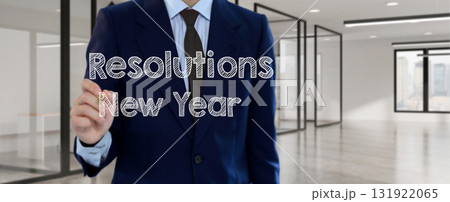 Businessman writing New Year Resolutions text on virtual screen inside modern office, symbolizing goal setting and ambition 131922065