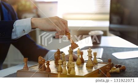 Businessman making checkmate move in chess game, symbolizing strategic decision and successful business planning 131922071
