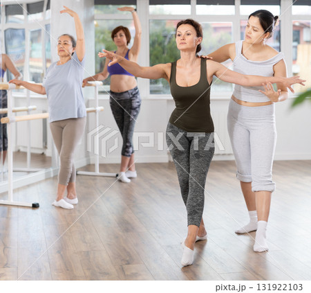 Female ballet teacher correcting posture of woman practicing in amateur class 131922103
