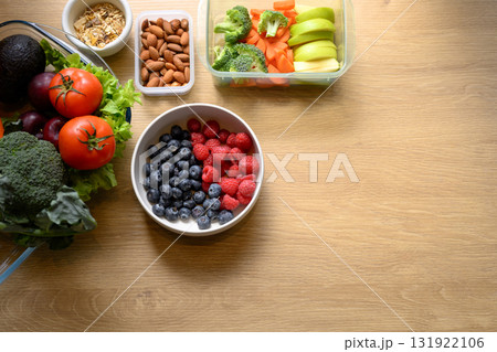 Top view of fresh ingredients with blueberries, raspberries, almonds, and vegetables on wooden table 131922106