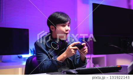 A young man enjoying playing computer games in a neon-lit room. The gaming atmosphere features vibrant colors A young man enjoying playing computer games in a neon-lit room. The gaming atmosphere features vibrant colors 131922143