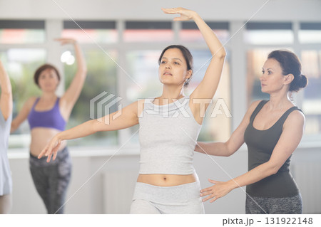 Asian woman enjoying ballet practice with instructor in group class Asian woman enjoying ballet practice with instructor in group class 131922148
