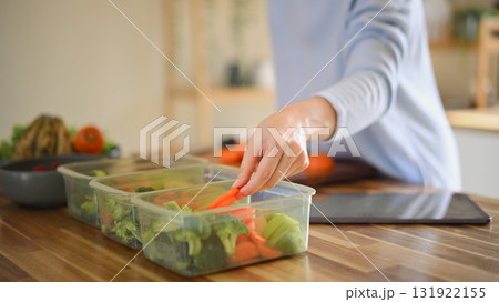 Closeup attractive woman arranging her dividing food into meals Closeup attractive woman arranging her dividing food into meals 131922155