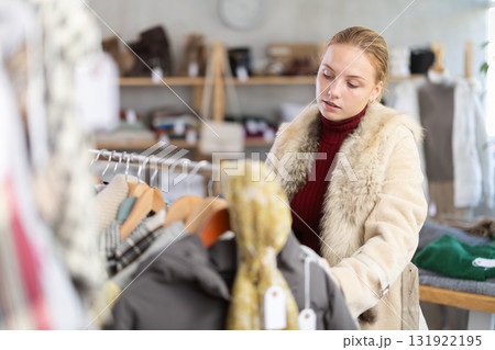 Attentive teenage girl choosing something for autumn-winter in clothing store 131922195