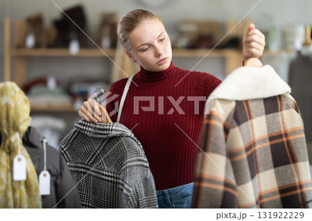 While shopping, teen girl browsing goods items and choose elect something warm outerwear in store While shopping, teen girl browsing goods items and choose elect something warm outerwear in store 131922229