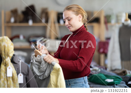 Attentive teenage girl choosing something for autumn-winter in clothing store 131922231