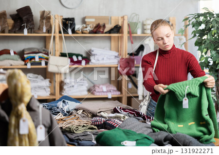 Selective teen girl choosing sweater in clothing store 131922271