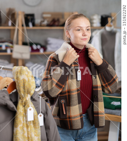 Selective teenage girl trying on winter coat in clothing store 131922292
