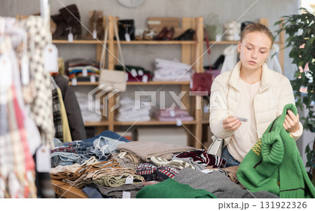 Selective teen girl choosing sweater in clothing store 131922326