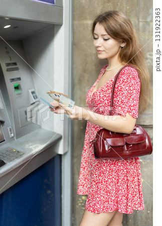 Young woman withdrawing a day from an atm 131922363