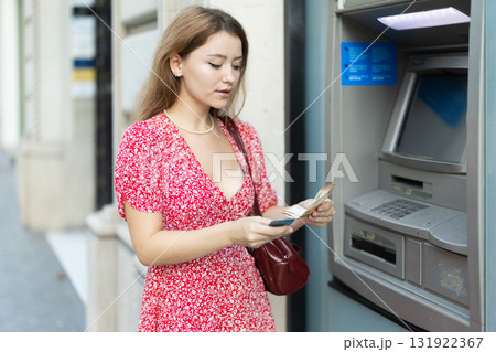 Young woman withdrawing a day from an atm 131922367