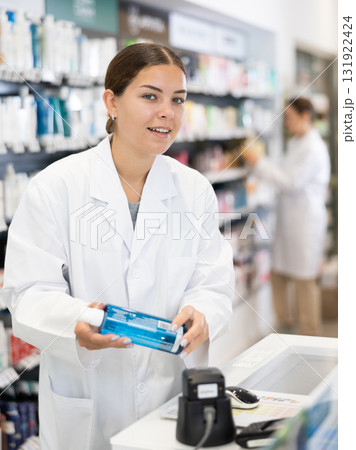 Young woman pharmacist scanning cosmetics at checkout 131922424