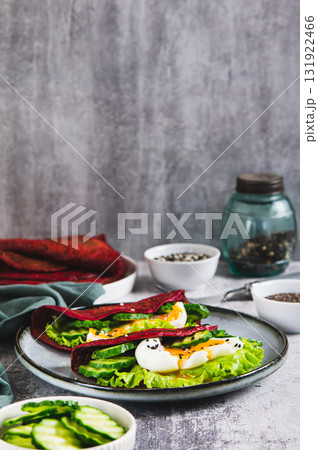 Beet chia tacos with egg, cucumber and lettuce on a plate on the table vertical view 131922466