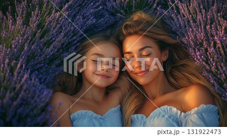 Mother and daughter resting in blooming lavender field at sunset, sharing tender moment together. Family bonding in natural environment 131922473