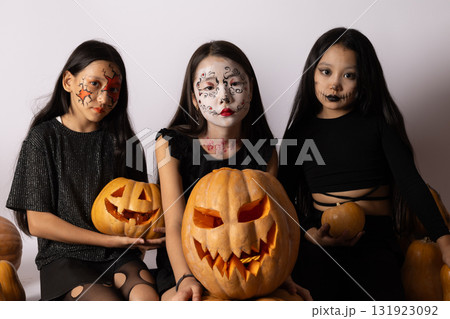 girls in Halloween costumes holding pumpkins 131923092