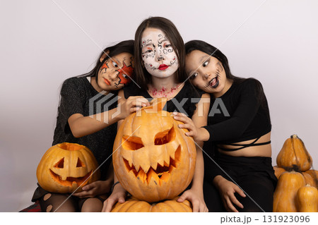 The three people are posing with painted faces for a Halloween-themed photo The three people are posing with painted faces for a Halloween-themed photo 131923096
