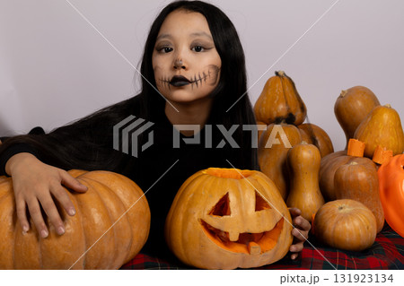 Girl with fake face holding pumpkin 131923134