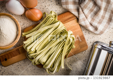 Green tagliatelle pasta on kitchen table. 131923667