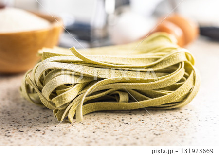 Green tagliatelle pasta on kitchen table. Green tagliatelle pasta on kitchen table. 131923669