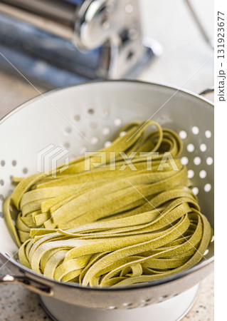 Green tagliatelle pasta in colander. 131923677
