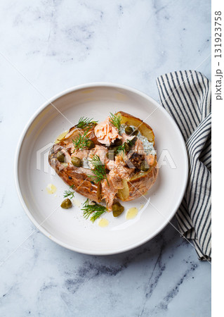 Whole baked potato stuffed with salmon, yogurt sauce and capers. 131923758