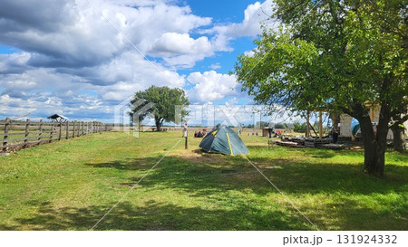 Camping in a tranquil setting with clouds and open fields under a blue sky during the day Camping in a tranquil setting with clouds and open fields under a blue sky during the day 131924332