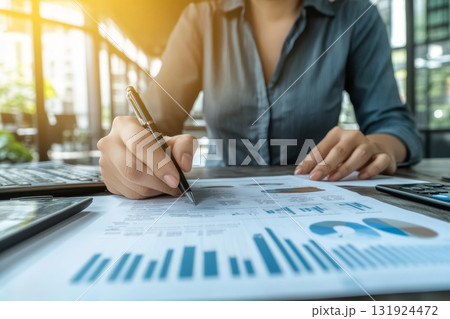 Female Financial Analyst Reviewing Stock Market Reports and Charts in a Modern Office Setting 131924472
