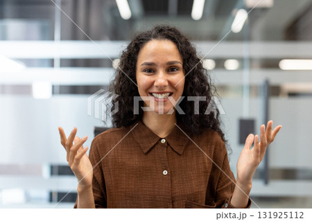 Young woman smiling at camera, having engaging conversation during online video conference, expressing happiness and optimism in modern corporate environment Young woman smiling at camera, having engaging conversation during online video conference, expressing happiness and optimism in modern corporate environment 131925112