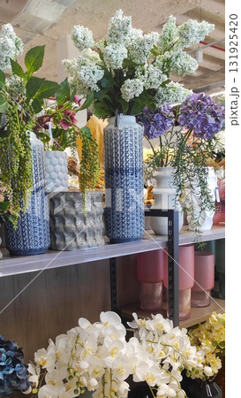Colorful floral arrangement displayed in decorative vases on a shelf, showcasing various textures and vibrant colors, creating a lively atmosphere in a modern interior space Colorful floral arrangement displayed in decorative vases on a shelf, showcasing various textures and vibrant colors, creating a lively atmosphere in a modern interior space 131925420