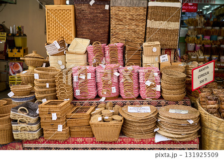 A shop display showcases a variety of handcrafted wicker baskets in different shapes, sizes, and designs, perfect for shopping and home decor. 131925509