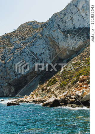 Beautiful coastal landscape with rugged cliffs and clear blue waters during a sunny afternoon Beautiful coastal landscape with rugged cliffs and clear blue waters during a sunny afternoon 131925548
