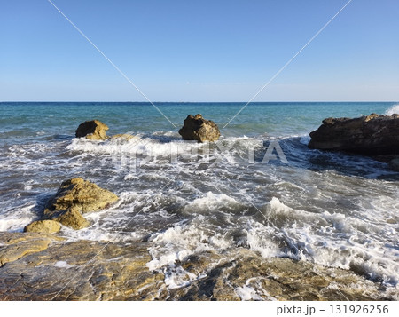 A tranquil seascape showcasing beautiful rocks and waves under a pristine clear blue sky A tranquil seascape showcasing beautiful rocks and waves under a pristine clear blue sky 131926256