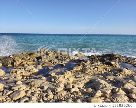 A picturesque and scenic Rocky Beach accompanied by clear blue ocean waves rolling in gracefully 131926266