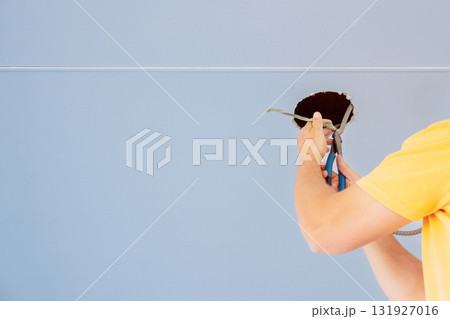 Worker uses tools to repair hole in ceiling light in contemporary indoor setting 131927016