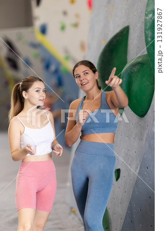 Female athletes communicate during break between workouts, gym climbing wall sport center 131927867