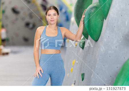 Girl in sports clothes standing near artificial climbing wall. Girl in sports clothes standing near artificial climbing wall. 131927873