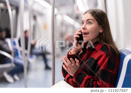 girl sitting in subway car with phone 131927887