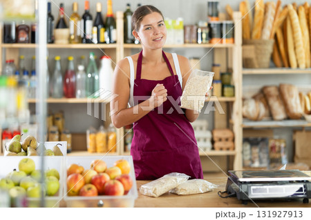 Young woman seller offering oat flakes in grocery store 131927913