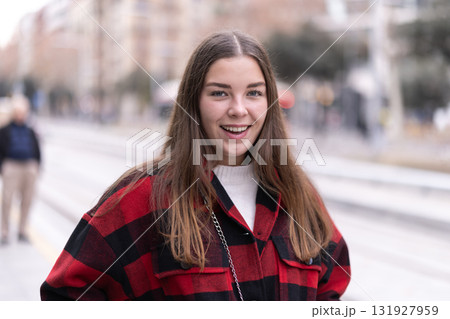 Girl is standing on street platform, waiting for tram to arrive 131927959