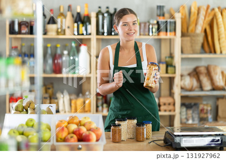 Young female seller offering beans in grocery store Young female seller offering beans in grocery store 131927962